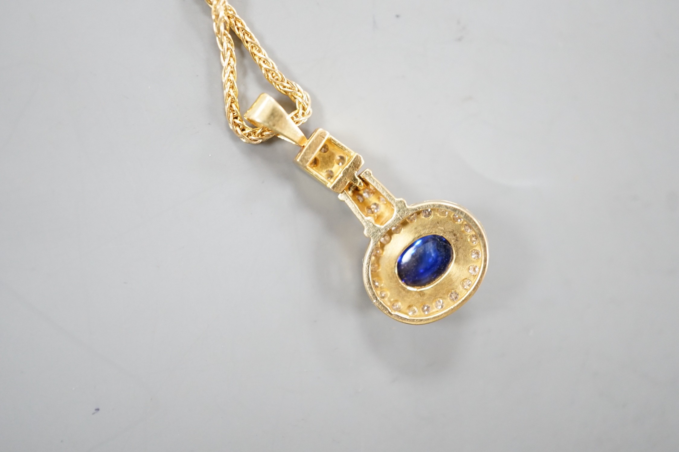 A modern yellow metal, cabochon sapphire and diamond set cluster pendant, overall 30mm, gross 4 grams, on a modern 9ct gold chain, 46cm, 4,3grams.